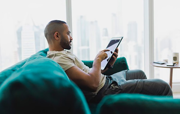 A man reading a tablet on a couch