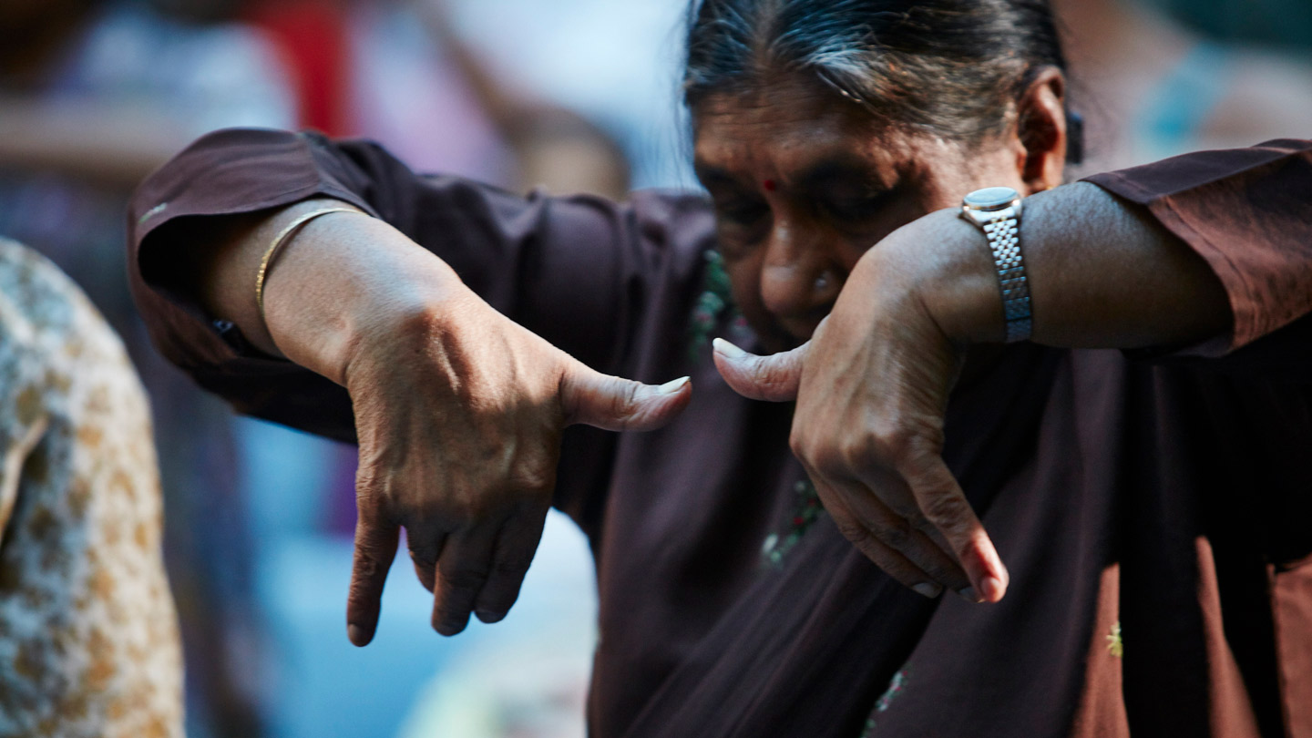 An elderly lady doing hand and arm exercises.