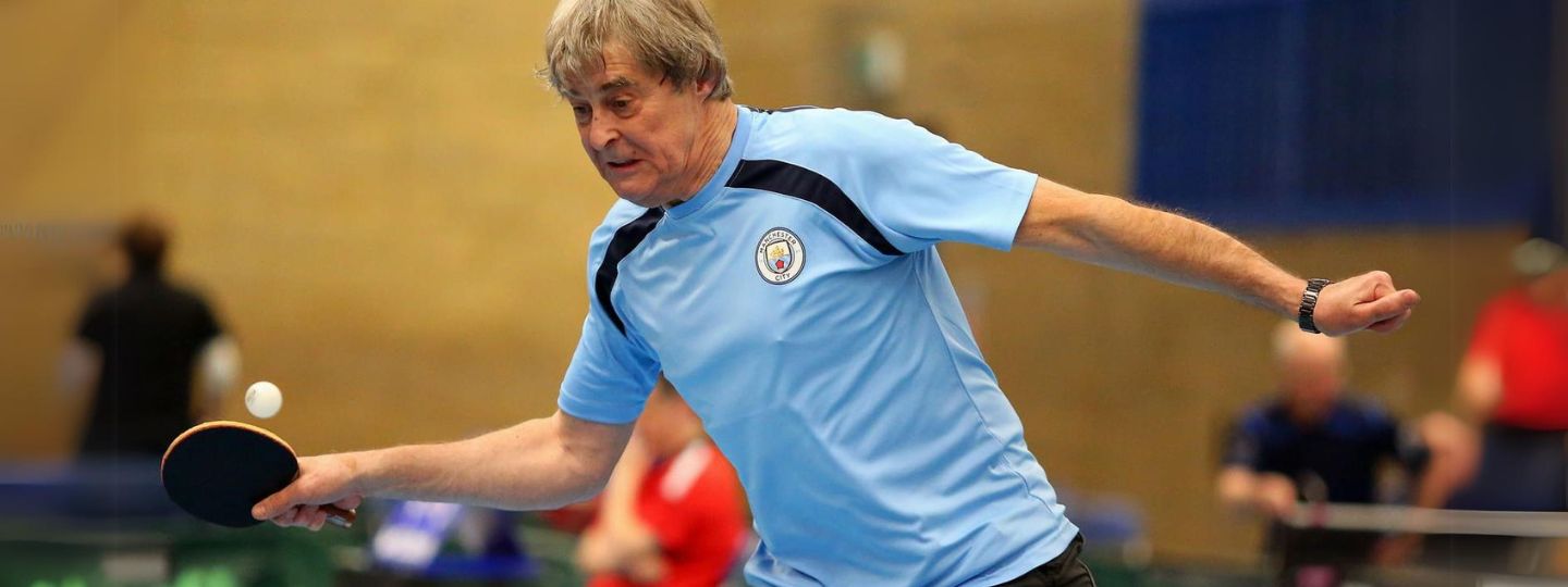 Nick playing table tennis wearing blue t-shirt