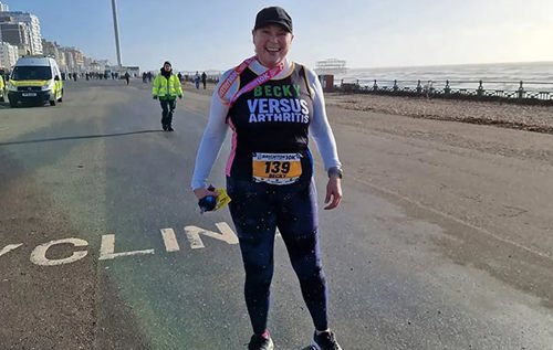 A woman training for a marathon, dressed in an Arthritis UK running vest.