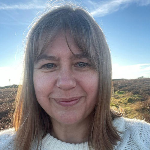 Jane Sutton smiling on a hill in the sun