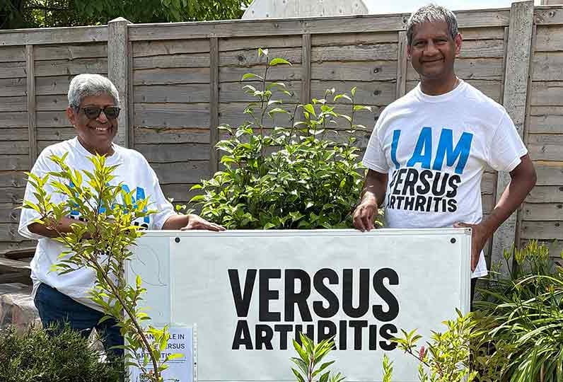 Meeta and her husband holding a versus arthritis banner in the garden
