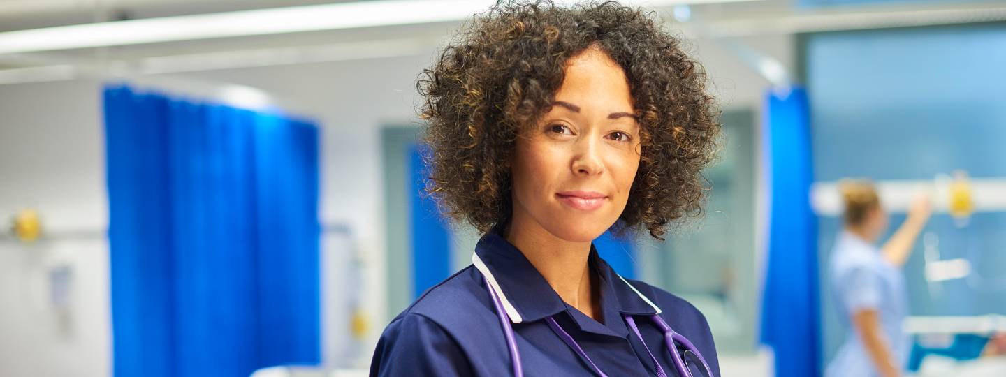 Smiling nurse wearing stethoscope and holding chart