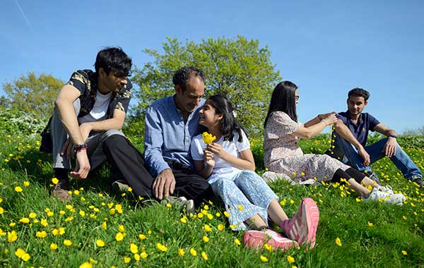 A family sat in a flowery field in the sun