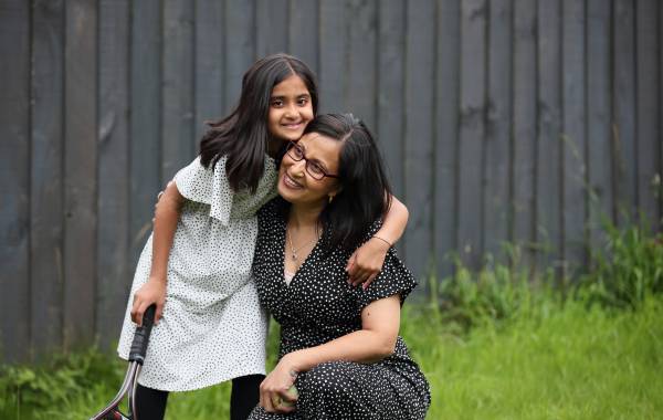 Smiling mother and daughter in the garden holding a tennis racket