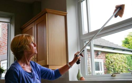 Woman cleaning windows using extendable duster