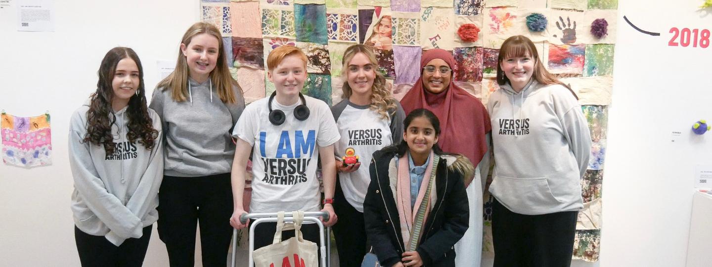 Group of smiling young people wearing Arthritis UK t-shirts at the Joint Creativity art exhibit