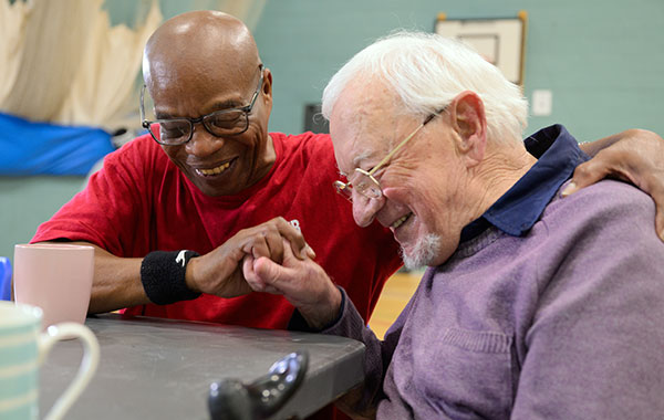 Two men with arthritis comforting each other while sharing a funny moment