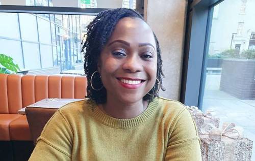 Smiling Ayo wearing red lipstick sitting in restaurant booth