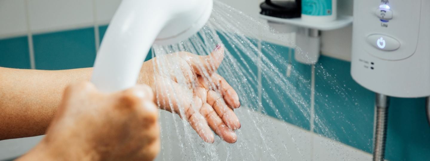 Woman using the shower in a blue and white tiled bathroom 